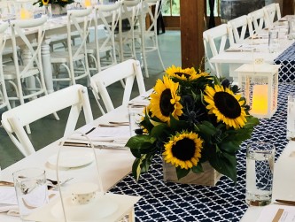 Rehearsal dinner in the barn with white farm tables and sunflowers